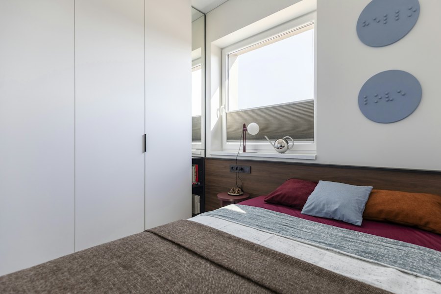 Quarto com armário branco do piso ao teto e cabeceira em madeira.