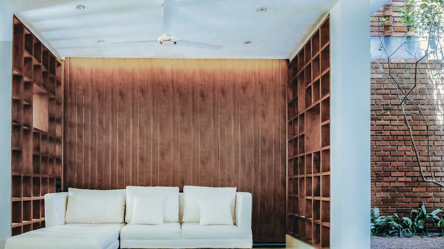 Estantes em treliça dos dois lados da sala: guardam livros e objetos e deixam a luz passar.
